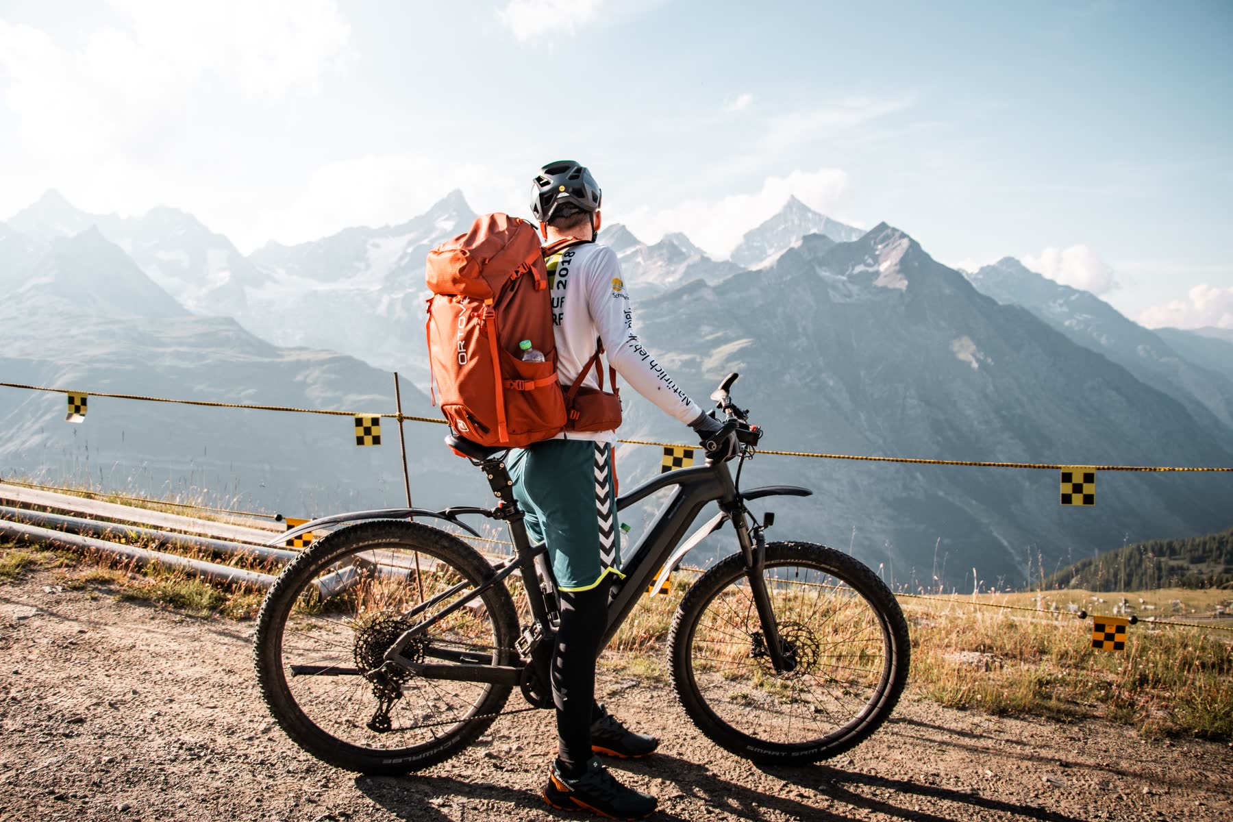 Vététiste contemplant les sommets du Valais avec son vélo