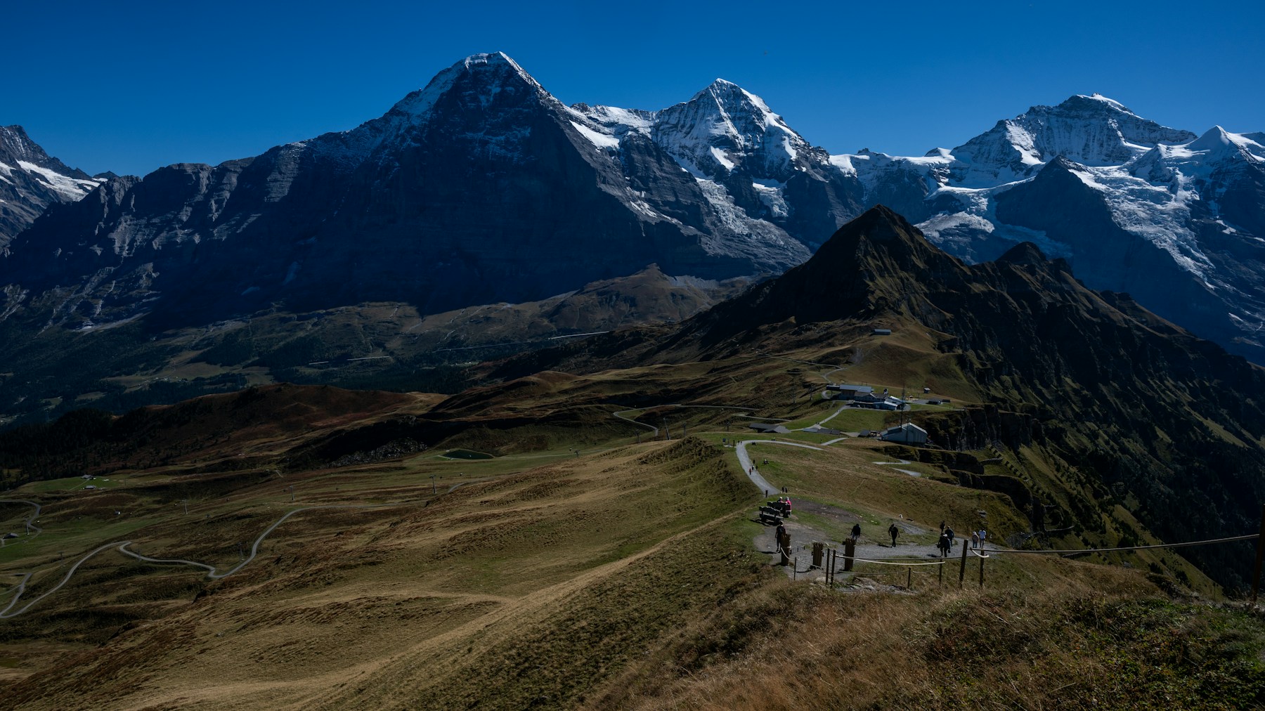 Randonneurs avançant sur une large crête des Alpes suisses