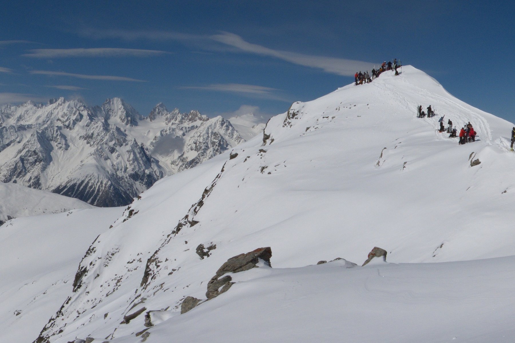 Groupe de skieurs de randonnée progressant sur la crête enneigée du Mont Rogneux